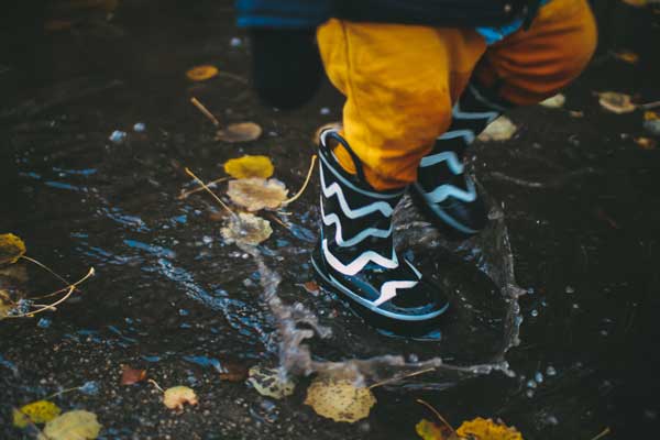 child putting his rubber boot in a puddle