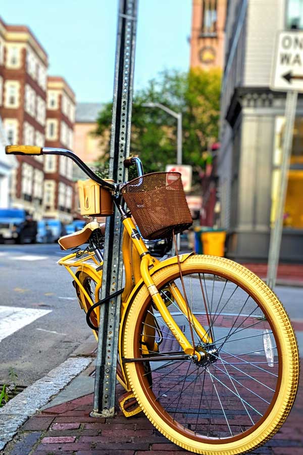 yellow bicycle tied to a pole in town