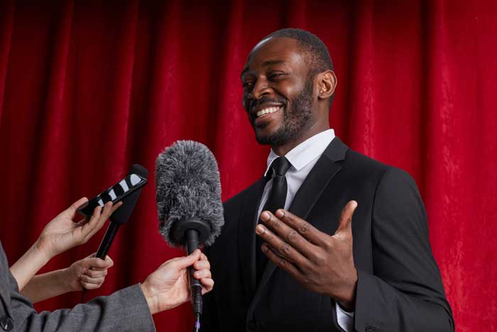 Portrait d'un homme afro-américain donnant un interview et parlant au micro devant un rideau en velours rouge
